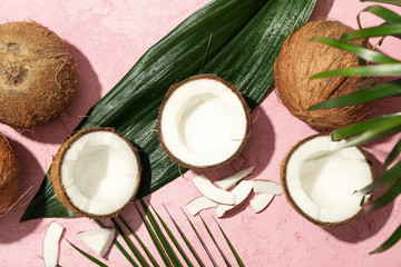 Coconut and palm leaves on pink background, top view