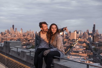 Happy Couple sits on rooftop overlooking Chicago