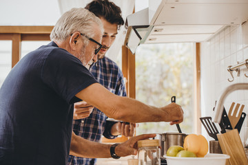 Elder cooking in the kitchen with his son, Happy family man moment good mentor old man care from...