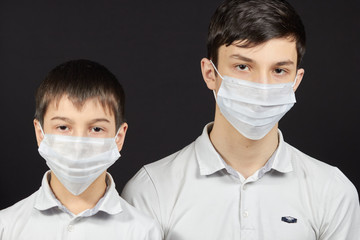 Teenager and boy in a mask in the black background