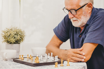 Smart Elder playing Chess board game at home for training brain memory and thinking happy smiling...