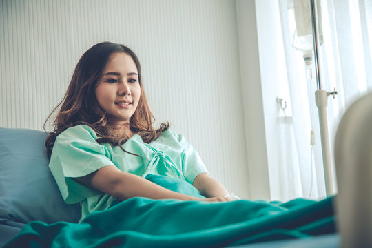 Woman Patient In Green Shirt Lying On Hospital Clinic Bed.