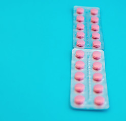 Pink tablets. Pills on a blue background, medical drugs.