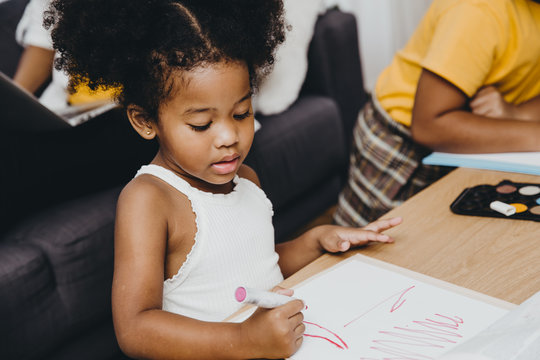 American Black Preschool Daughter Kids Doing Homework Learning Education With Her Sister Living Together At Home.