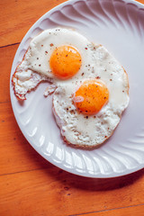 Fried eggs with salt and pepper on a plate from above