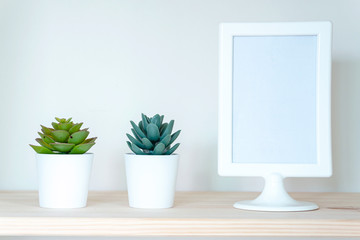Mock up white frame and home plant on table. Home decoration