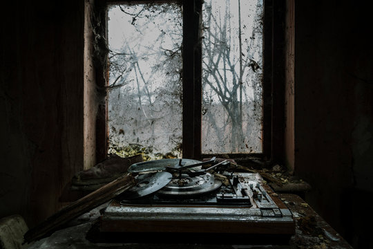 Old record player by window in abandoned house