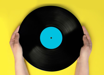 Woman's hands holding a vinyl record. Yellow background