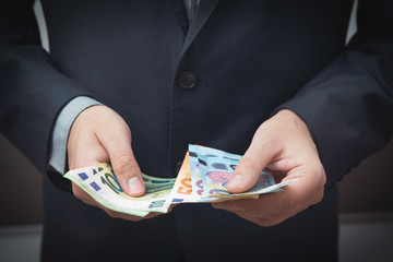 Man in a suit counts Euro banknotes