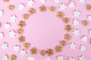 Top view on white and brown sugar in the shape of flowers. Round frame on a pink background
