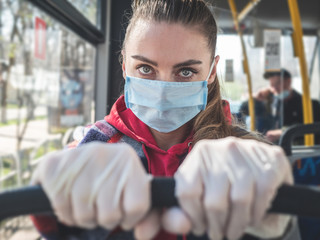 Woman in protective medical mask and gloves in bus. Public transport during coronavirus covid-19 pandemic.