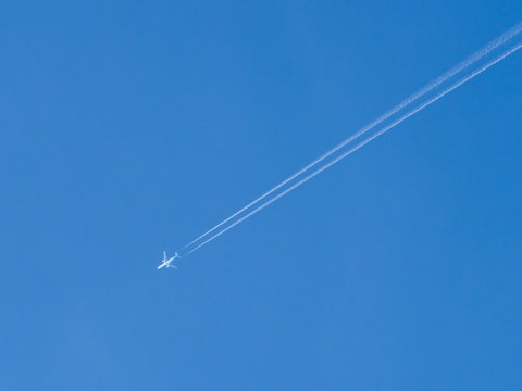 Passenger aircraft seen against a clear blue sky, photographed from Firle Beacon, a hill on the South Downs Way, East Sussex, England.