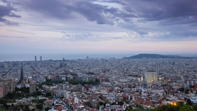 Sunset to night timelapse over the Skyline of Barcelona with cathedral Sagrada Familia and mountain Montjuic, from the top of Bunkers del Carmel, moving clouds in sky, Spain
