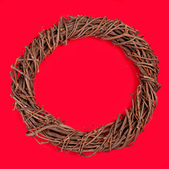 Braided vine wreath on a red background. The view from the top. Handmade from natural material. It is used in floral design to create arrangements for holidays, Christmas, Christmas decor.