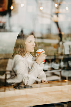 Beautiful young girl sitting and enjoing coffee in restaurant