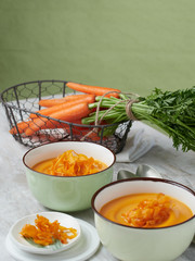 sopa de zanahoria en cuenco para servir con zanahorias frescas al fondo