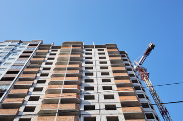 Fototapeta premium Tower crane building a house. Concrete building under construction. Construction site