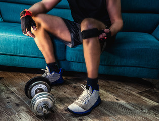 Man closing a knee strap sitting on the couch