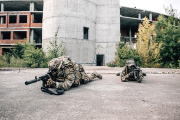 Two snipers in camouflage lying on the ground aiming at the enemy