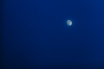 The moon in the night sky. Blue sky and white moon, night background.
