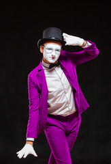 Portrait of male mime artist, isolated on black background. Man in a purple suit is happily posing...