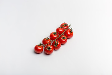 Beautiful juicy red cherry tomatoes on a branch on a white background