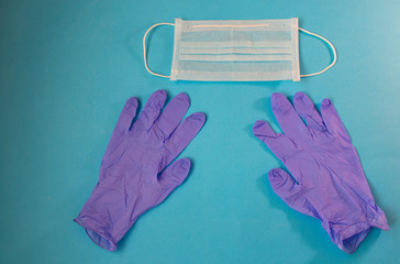 Protective agents for the treatment of the COVID-19 virus. Surgical mask and latex gloves on a blue background
