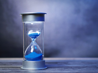 Vintage hour glass with blue sand. A symbol of time with copy space for titles