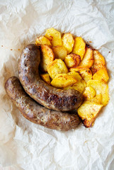 On parchment paper, a traditional German dish, potatoes and fried sausages