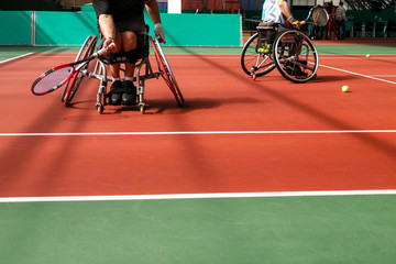 Disabled mature men on a wheelchair playing tennis on an indoor tennis court. Copy space