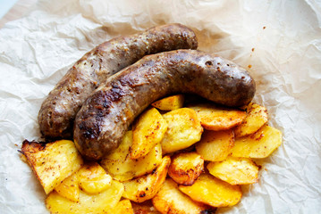 On parchment paper, a traditional German dish, potatoes and fried sausages