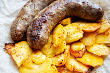 On parchment paper, a traditional German dish, potatoes and fried sausages