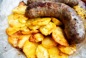 On parchment paper, a traditional German dish, potatoes and fried sausages