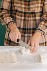 Woman cuts pieces of dough to prepare her handmade bread, homemade cooking.