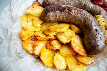 On parchment paper, a traditional German dish, potatoes and fried sausages