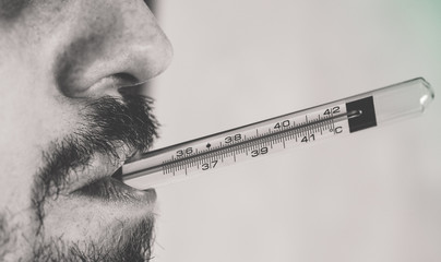 Man checking on his fever with a thermometer