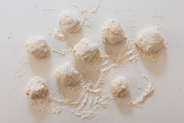 Handmade pieces of dough for bread on a white marble background, homemade cooking.