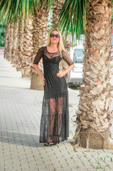 Blonde in a black  dress on the street with palm trees