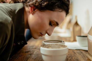 Mujer joven blanca oliendo tazas de café en una cata brasileña