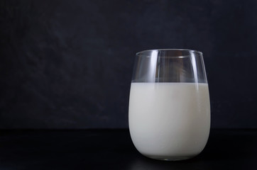milk in a beautiful glass with highlights on a dark background with reflection with place for text