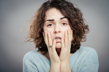 Closeup portrait of young, upset, sad depressed, worried, troubled brunette woman holding her head with both hands, isolated. Human emotions, face expressions, feelings, perception