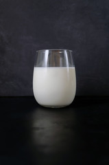 milk in a beautiful glass with highlights on a dark background with reflection with place for text