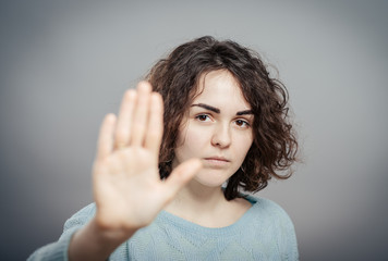 Serious young woman showing stop gesture, isolated
