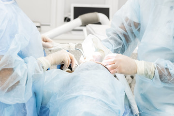 Close-up of the hands of a dentist and nurse surgeon over an operating room during a dental implant...