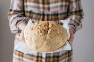Woman holding tasty fresh handmade bread, in her home,  close up