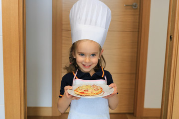 Preschool girl, wearing a shirt with the Spanish Flag, proudly showing a home-made mini-pizza, during coronavirus quarantine in Spain.