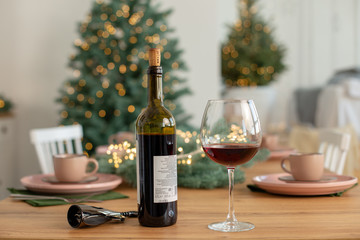 Bottle of red wine and a glass on the background of the Christmas tree