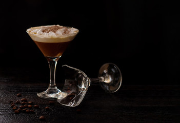 Martini glass and Baileys on a black background. a broken glass is next to it. horizontal banner for designers