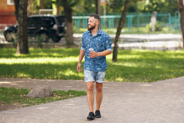 Fototapeta premium A young guy walking in the park with lemonade in the spring. Spring day.