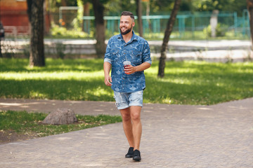 Obraz premium A young guy walking in the park with lemonade in the spring. Spring day.